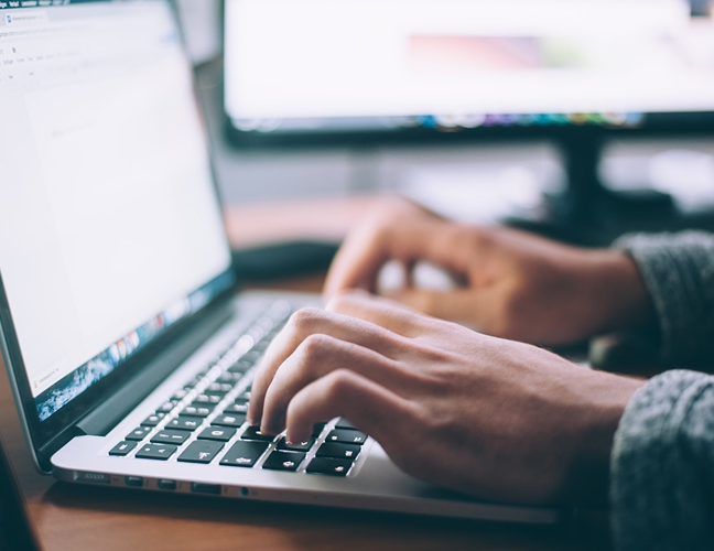 Hands typing on laptop